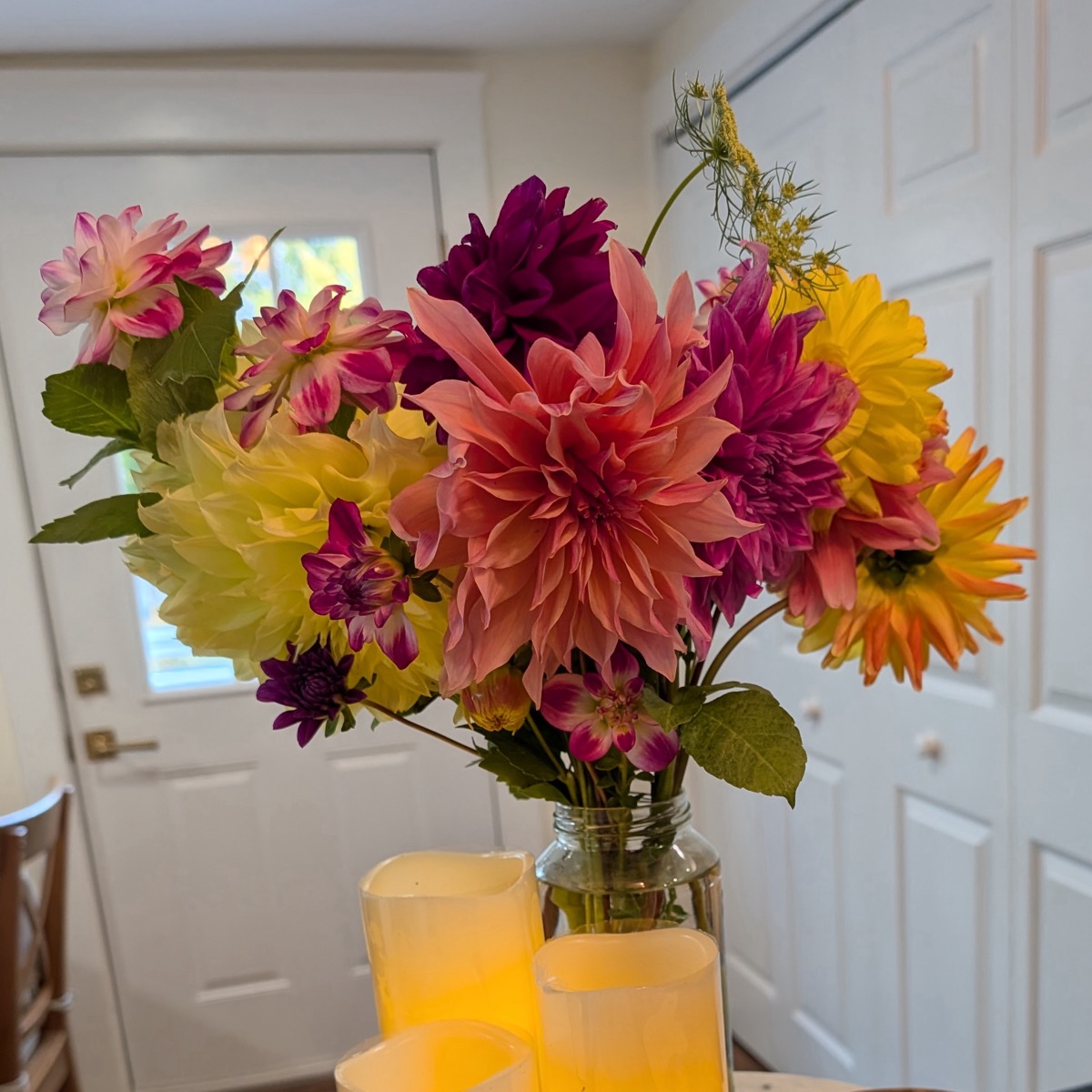 Large dahlia bouquet in pink, purple and yellow in a glass jar